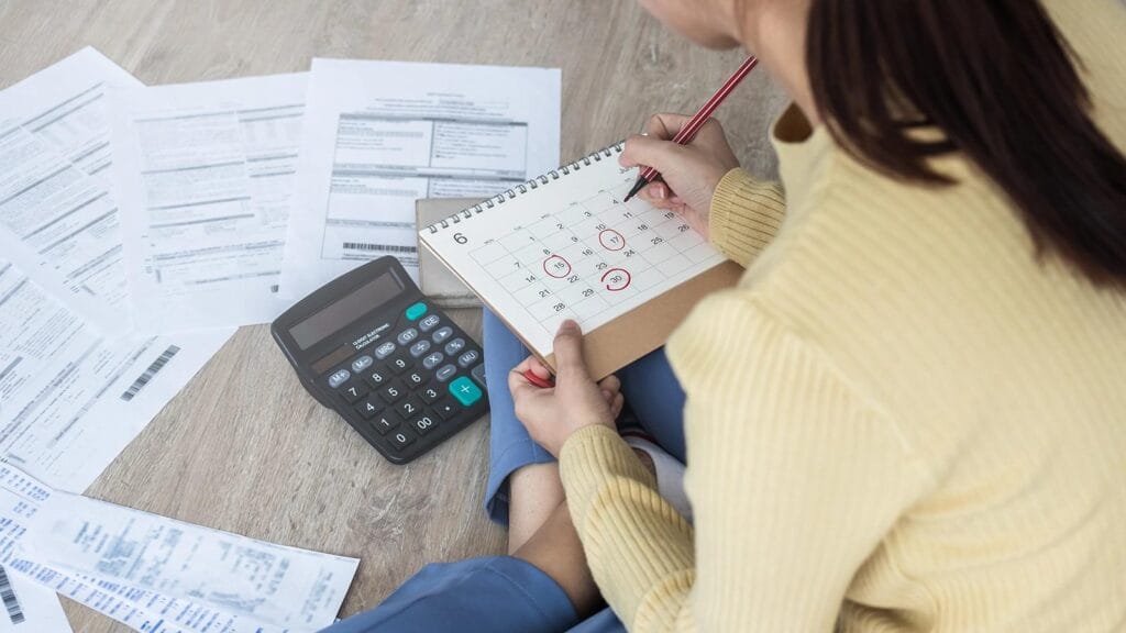 Pessoa analisando boletos e calendário para entender se a dívida prescreve depois de 5 anos.