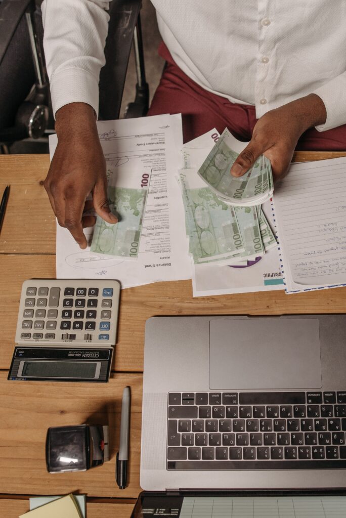 Pessoa organizando um orçamento mensal simples com dinheiro, calculadora e contas