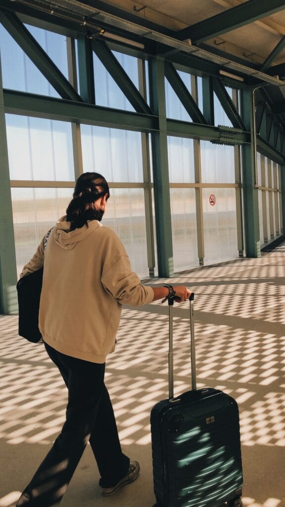 Pessoa caminhando no aeroporto para uma viagem utilizando milhas obtidas com promoções de transferência bonificada.