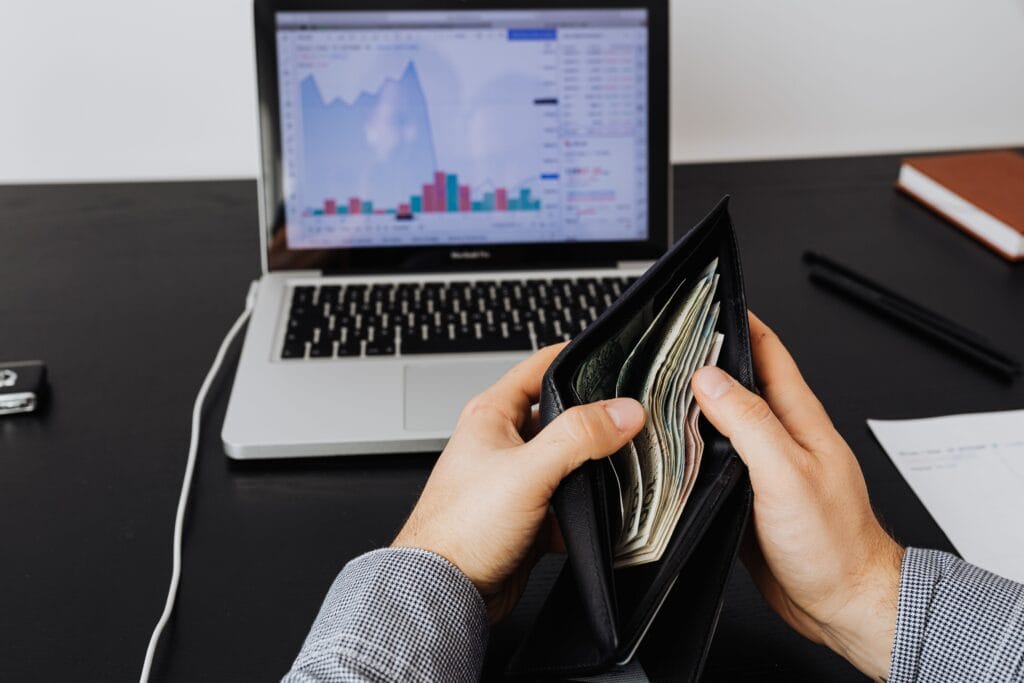 Pessoa segurando carteira com dinheiro enquanto analisa investimentos que rendem pelo CDI