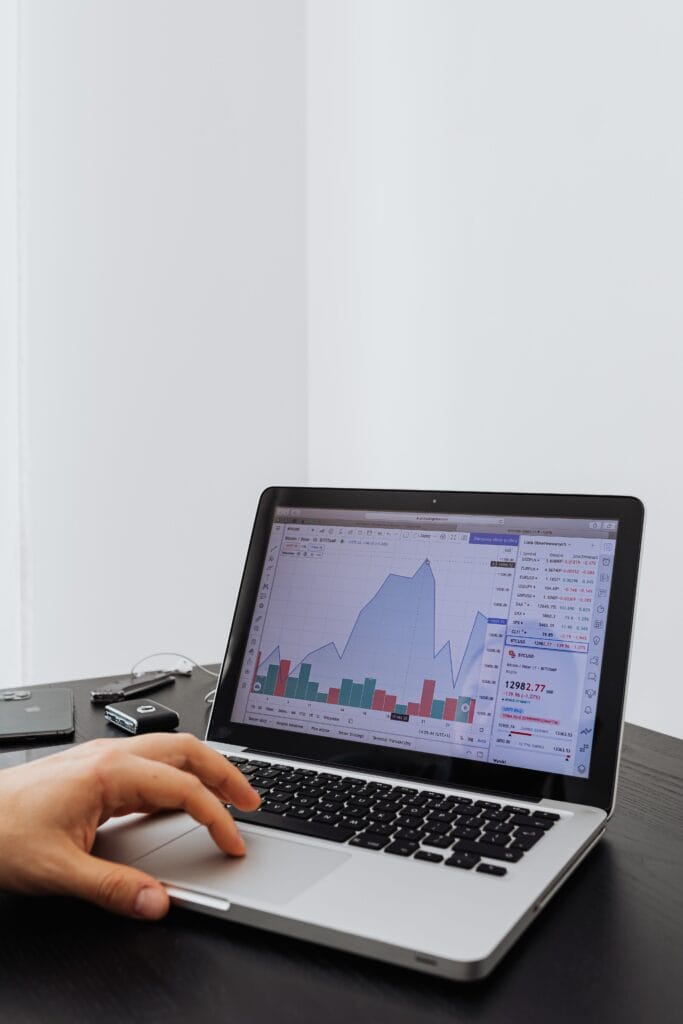 Pessoa analisando gráficos de investimentos em notebook para aprender sobre Fundos Imobiliários para Iniciantes.