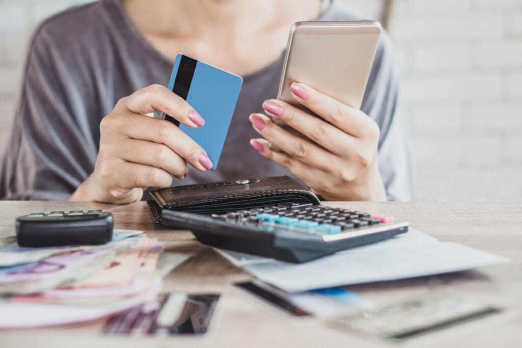 Pessoa organizando gastos do cartão de crédito pelo celular durante planejamento financeiro