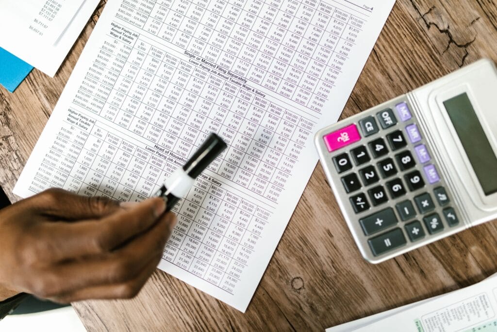Pessoa analisando valores financeiros com calculadora e documentos