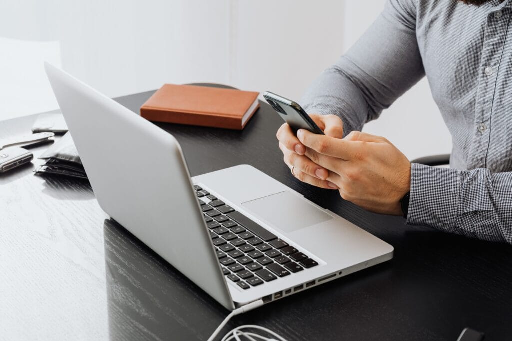 Pessoa analisando empréstimo para pagar dívidas pelo celular e computador