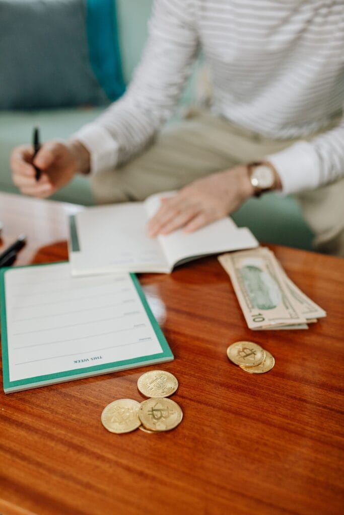 Pessoa planejando o orçamento financeiro com caderno, dinheiro e calculadora