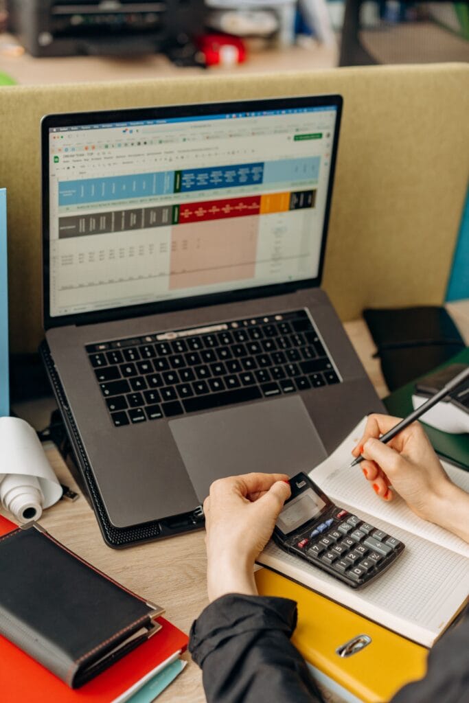 Pessoa organizando um plano financeiro pessoal com notebook e calculadora