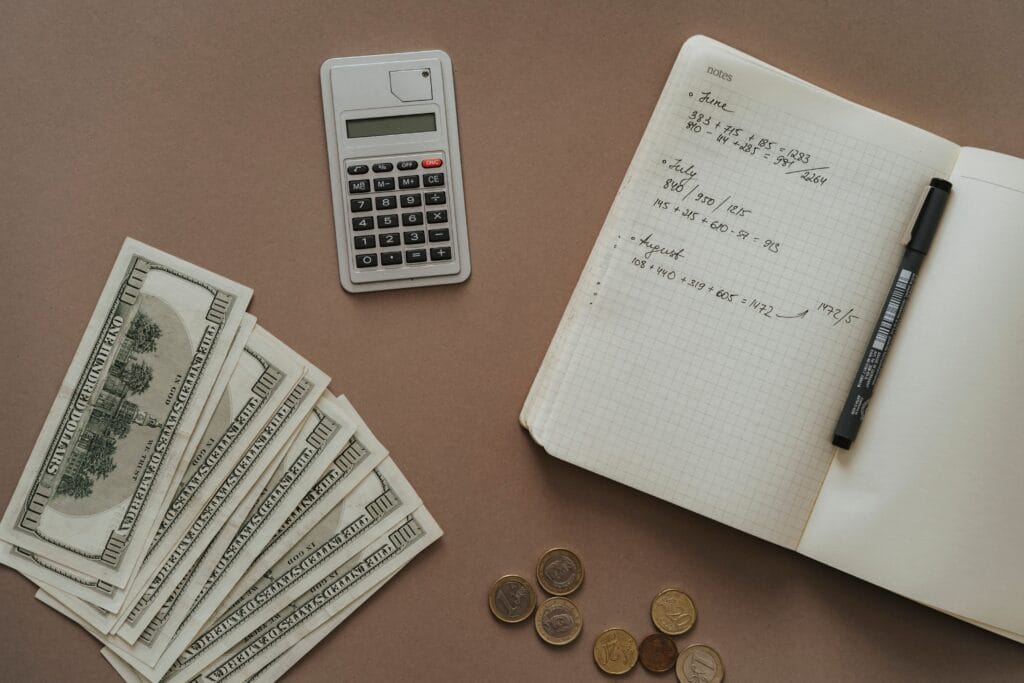 Pessoa organizando as finanças do mês com planilha, calculadora e celular